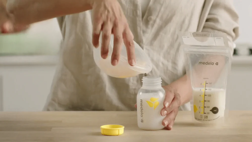 Madre vaciando leche materna en una bolsa de almacenamiento Medela